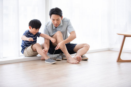 Chinese father teaching his son to tie shoelaces