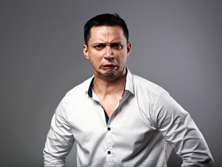 Pout grimacing angry business man looking aggressive on grey background. Closeup
