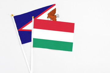 Hungary and American Samoa stick flags on white background. High quality fabric, miniature national flag. Peaceful global concept.White floor for copy space.