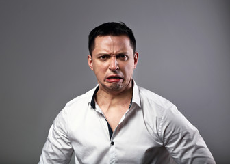 Obraz premium Pout grimacing angry business man looking aggressive on grey background. Closeup