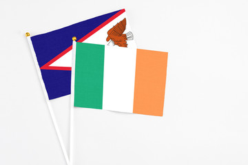 Ireland and American Samoa stick flags on white background. High quality fabric, miniature national flag. Peaceful global concept.White floor for copy space.