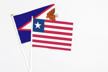 Liberia and American Samoa stick flags on white background. High quality fabric, miniature national flag. Peaceful global concept.White floor for copy space.