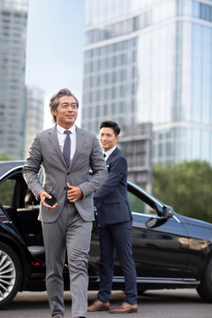 Confident Chinese businessman getting out of car