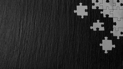 White puzzle in the corner of the image on a black natural stone background of slate. A frame with...