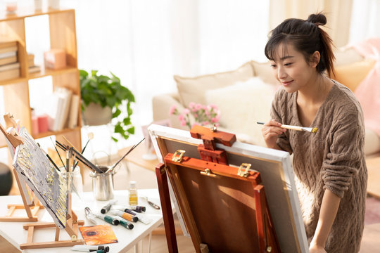 Young Chinese woman painting at home
