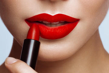 Beautiful girl with red lips and classic makeup with lipstick in hand. Beauty face - obrazy, fototapety, plakaty