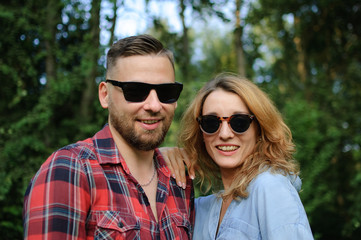 Young couple in sunglasses spending time together and walking in the spring park