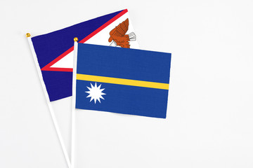 Nauru and American Samoa stick flags on white background. High quality fabric, miniature national flag. Peaceful global concept.White floor for copy space.