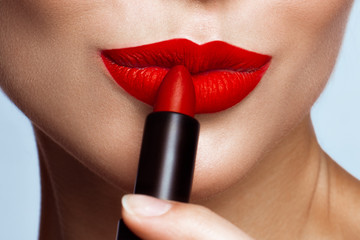 Beautiful girl with red lips and classic makeup with lipstick in hand. Beauty face