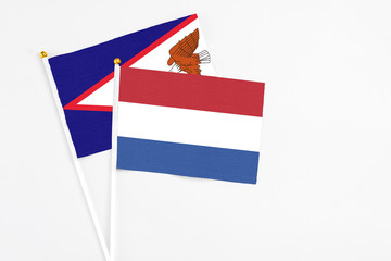 Netherlands and American Samoa stick flags on white background. High quality fabric, miniature national flag. Peaceful global concept.White floor for copy space.