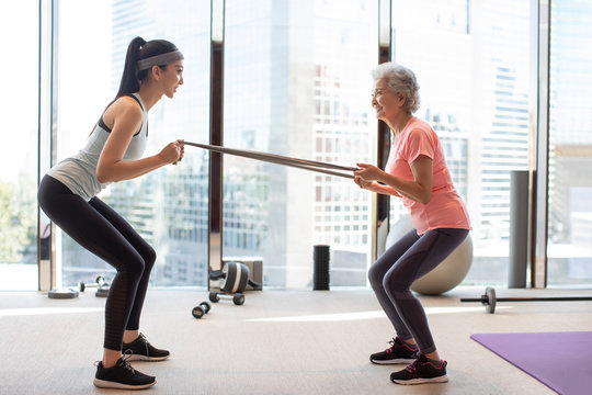 Senior Chinese woman working out with personal trainer at gym - Powered by Adobe