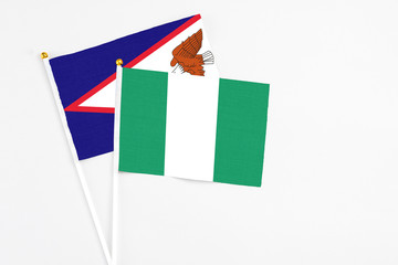 Nigeria and American Samoa stick flags on white background. High quality fabric, miniature national flag. Peaceful global concept.White floor for copy space.