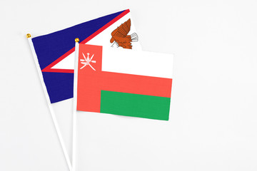 Oman and American Samoa stick flags on white background. High quality fabric, miniature national flag. Peaceful global concept.White floor for copy space.