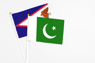 Pakistan and American Samoa stick flags on white background. High quality fabric, miniature national flag. Peaceful global concept.White floor for copy space.