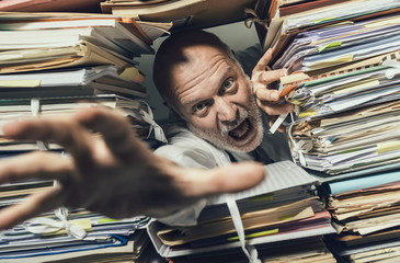 Panicked businessman overloaded with paperwork