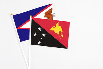 Papua New Guinea and American Samoa stick flags on white background. High quality fabric, miniature national flag. Peaceful global concept.White floor for copy space.