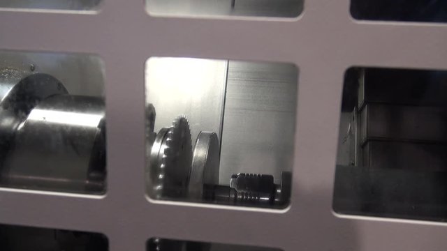 A machine gives an industrial soap shower to a disk-shaped piece of metal in a shower chamber in a metal industry where different types of pieces are manufactured.