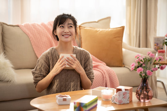 Young Chinese woman holding gift box at home