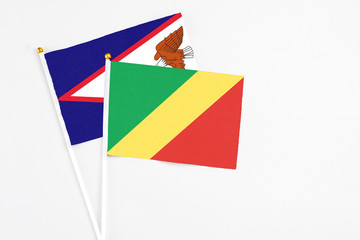 Republic Of The Congo and American Samoa stick flags on white background. High quality fabric, miniature national flag. Peaceful global concept.White floor for copy space.