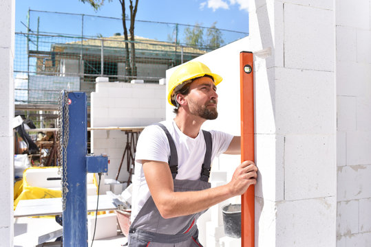Bauarbeiter beim Hausbau mit Wasserwwage // profession construction worker - work on a building site construction of a residential house