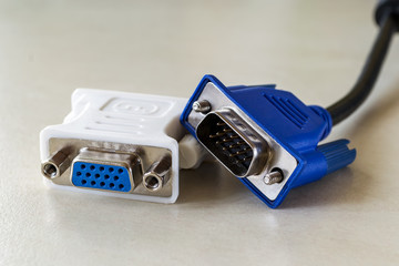 Vga plug of white dvi-d adapter and blue vga socket monitor cord near it. Connection of computer devices with plugs of different types.
