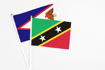 Saint Kitts And Nevis and American Samoa stick flags on white background. High quality fabric, miniature national flag. Peaceful global concept.White floor for copy space.