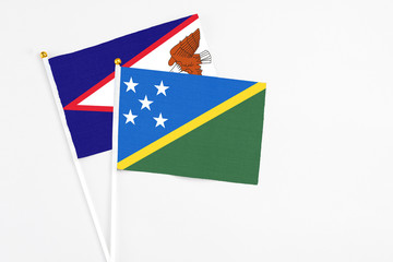 Solomon Islands and American Samoa stick flags on white background. High quality fabric, miniature national flag. Peaceful global concept.White floor for copy space.