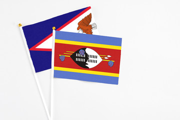 Swaziland and American Samoa stick flags on white background. High quality fabric, miniature national flag. Peaceful global concept.White floor for copy space.