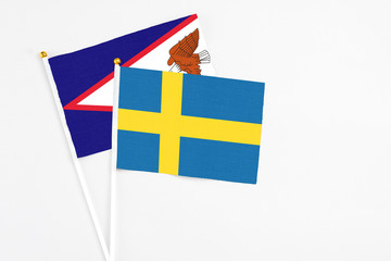 Sweden and American Samoa stick flags on white background. High quality fabric, miniature national flag. Peaceful global concept.White floor for copy space.