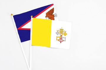 Vatican City and American Samoa stick flags on white background. High quality fabric, miniature national flag. Peaceful global concept.White floor for copy space.