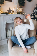 Close up portrait of young cheerful blondie stylish caucasian woman in christmas decorations at cozy home. Holiday, new year concept