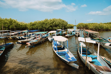 Gambia - August 4, 2019: Picturesque pier with wooden boats on crystal water on shore