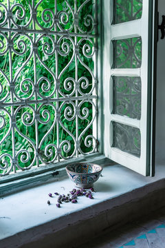 Small dried flower buds and ornamental bowl placed near open window inside traditional Arabic home in Marrakesh, Morocco