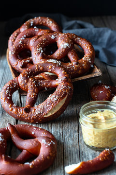 Fresh appetizing pretzels with salt arranged on scoop over old wooden surface