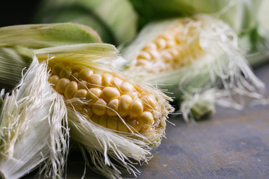Top view of steps of fresh ripe corn peeling on black table