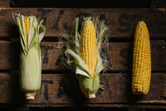 Top view of steps of fresh ripe corn peeling on wooden table