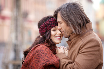 Happy couple posing on the old square of the city. Pretty beautiful woman and her handsome stylish man hugging on the street. Autumn or winter time. Close up image