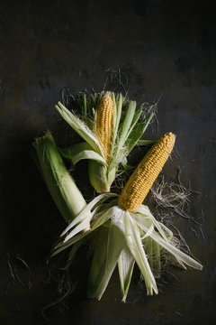 Top view of steps of fresh ripe corn peeling on black table