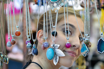 Trendy hipster asian woman looking for fancy jewelry and accessories in a flea market shop