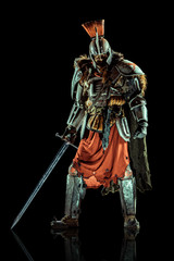 Fototapeta premium Powerful knight in the armor with the sword. Isolated on black background.