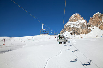 Chair lift with skiers in sunny day in mountains, Italy
