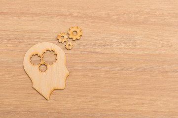 Business and design concept - wooden man head silhouette with gear icon on wooden background