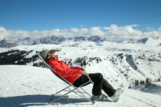 woman-skier  on a sun lounger in the mountains in winter