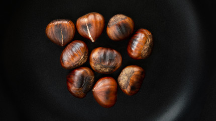 Chestnut on a black frying pan, top view. Roasted Chestnuts close-up, xmas food concept