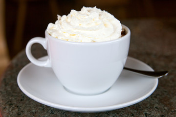Cup of hot chocolate with whipped cream and a piece of cake