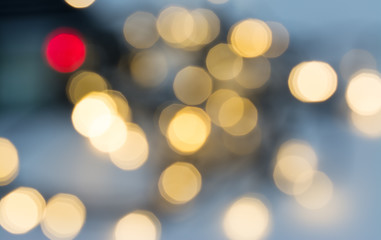 Blurred golden Christmas decorative lights glittering on blue foggy background with festive mood. Abstract glowing Xmas and New Year decorations. Red and yellow defocused LED lamps with bokeh effect.