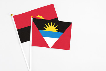 Antigua and Barbuda and Angola stick flags on white background. High quality fabric, miniature national flag. Peaceful global concept.White floor for copy space.