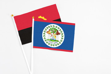 Belize and Angola stick flags on white background. High quality fabric, miniature national flag. Peaceful global concept.White floor for copy space.