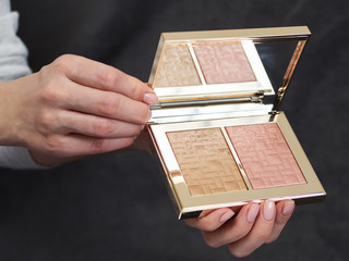 Woman's beauty blogger hands holding professional hi-end tone base cosmetics palette with blurred...
