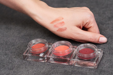 Woman's beauty blogger hand holding professional hi-end tone blush cosmetics set with blurred grey...